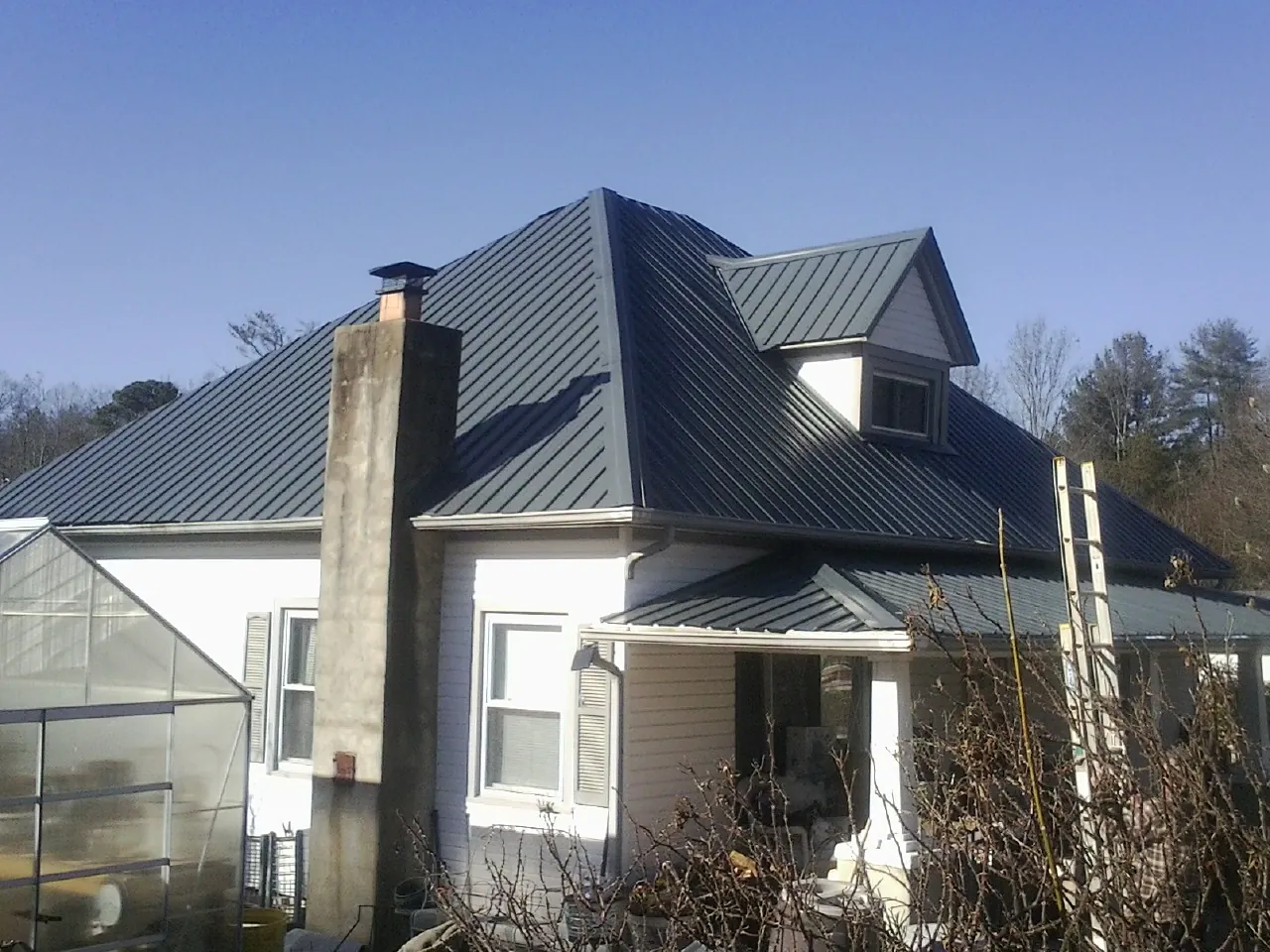 Dark blue standing seam metal roof on a white farmhouse with dormer — Slate & Tile Roof Repair by Roofing Brothers in Flossmoor