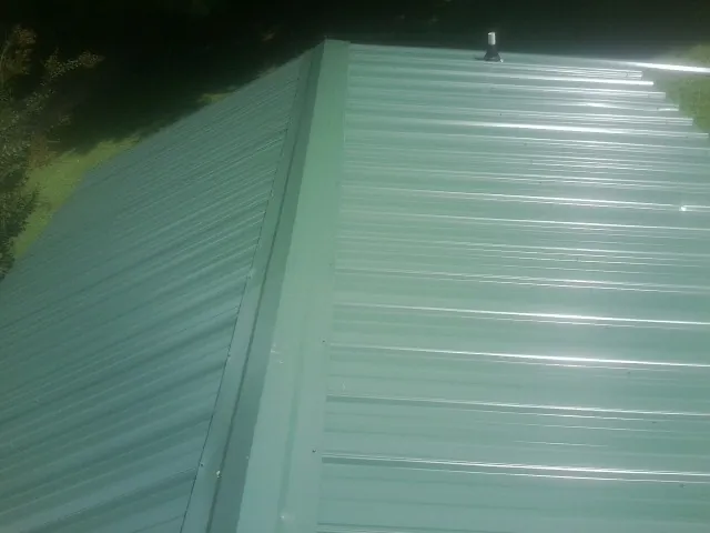 New green metal panels meeting at the ridge of a roof — Flat Roof Repair work by our crew in Flossmoor