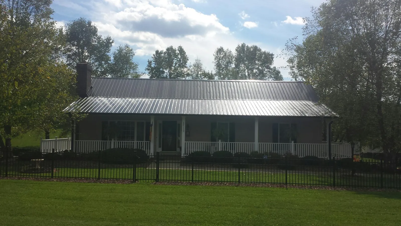 Gray metal roof on a brick ranch with a full width front porch — Gutter Guard Installation work by our crew in Flossmoor
