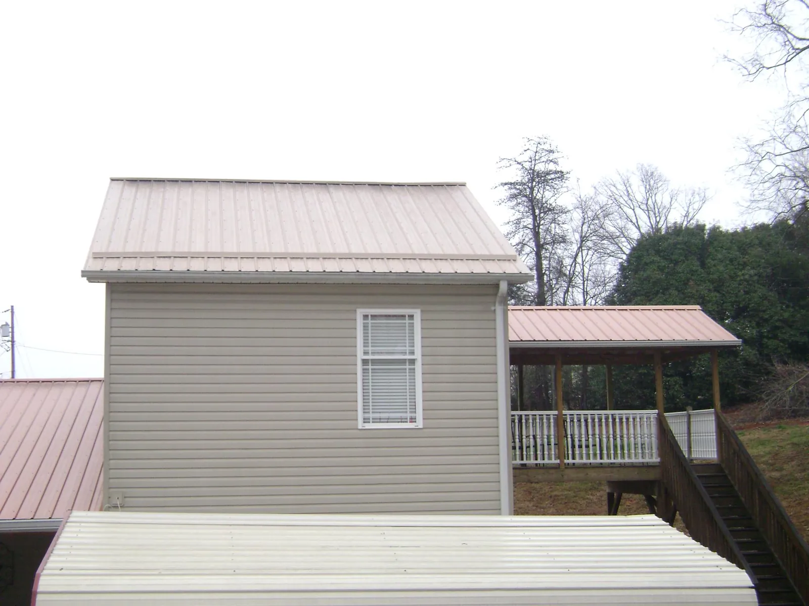 Tan metal roofs on a two story addition and attached porch, from a Roof Replacement job in Flossmoor
