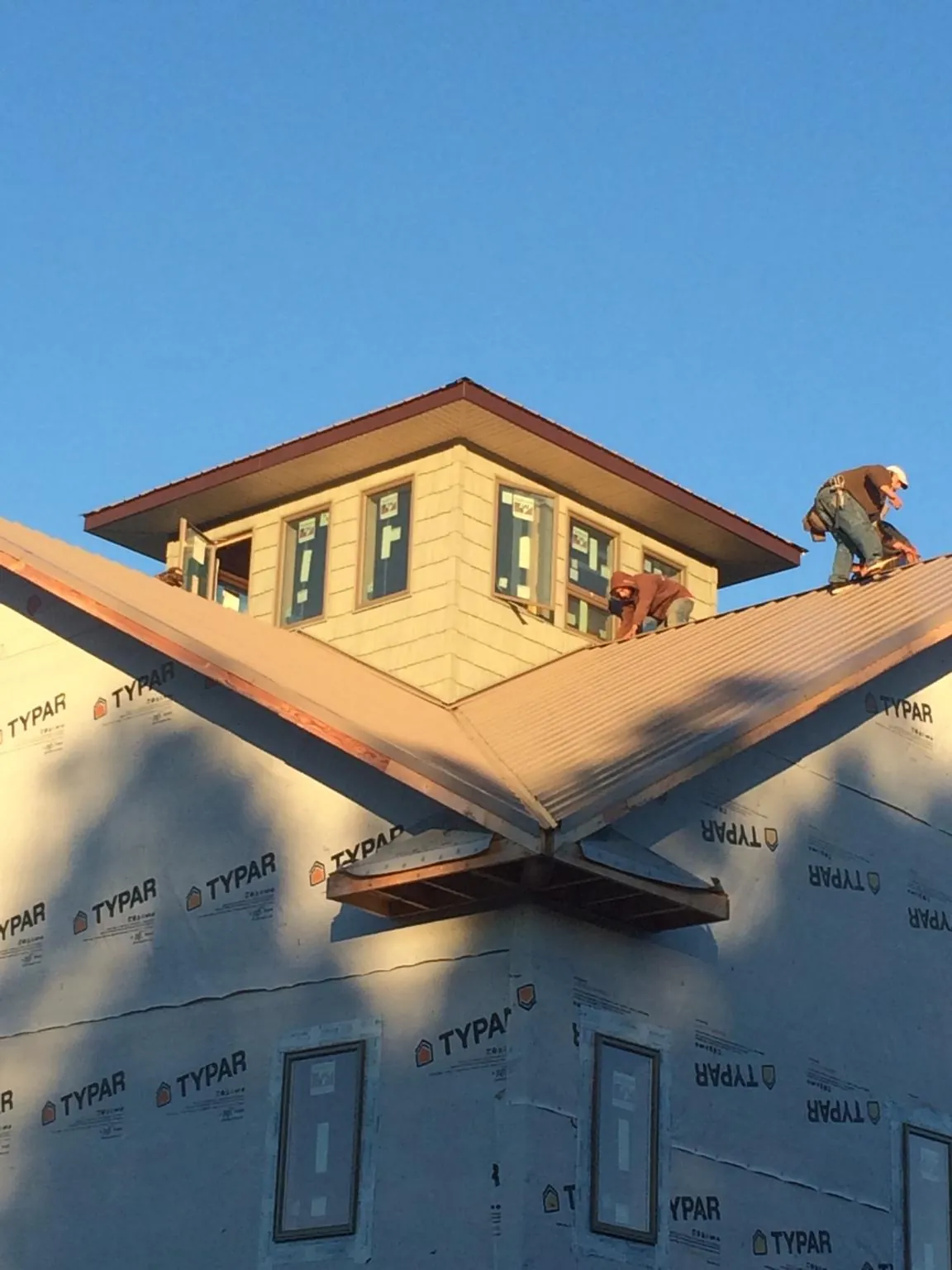 Roofers working around a rooftop cupola on a new metal roof at sunset — Roof Waterproofing in Flossmoor by Roofing Brothers